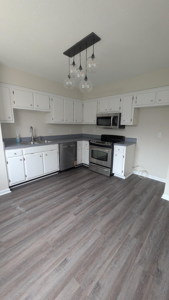 106 Beech Forge Dr, Antioch, TN 37013 - kitchen featuring stainless steel appliances, white cabinets, dark wood-style floors, hanging light fixtures, and dark countertops