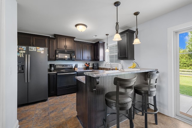 3228 Marion Davis Dr, Murfreesboro, TN 37129 - kitchen with black appliances, a kitchen bar, a peninsula, hanging light fixtures, and dark brown cabinetry