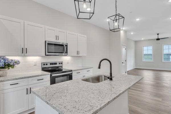 179 Charleston Ave, Pleasant View, TN 37146 - kitchen with appliances with stainless steel finishes, an island with sink, light wood-type flooring, white cabinetry, and decorative backsplash