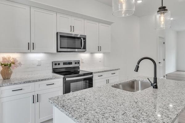 183 Charleston Ave, Pleasant View, TN 37146 - kitchen featuring stainless steel appliances, an island with sink, white cabinetry, decorative backsplash, and light stone countertops