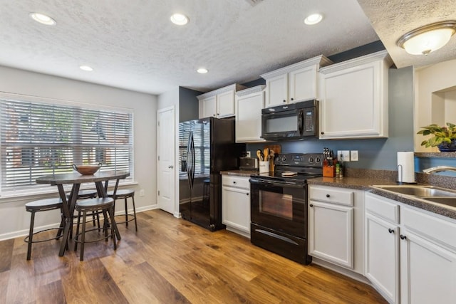 2058 Caladonia Way, Smyrna, TN 37167 - kitchen with black appliances, a textured ceiling, dark countertops, recessed lighting, and wood finished floors