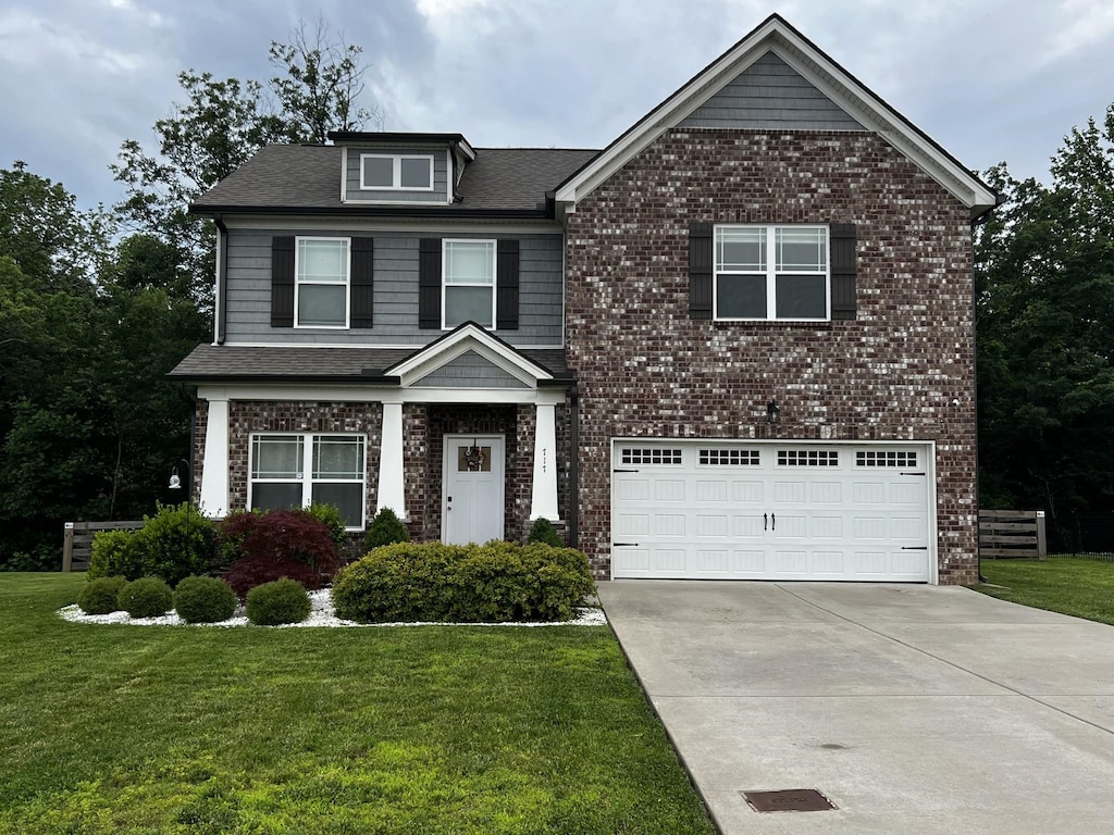 717 Monarchos Bnd, Burns, TN 37029 - view of front of home with concrete driveway, a garage, a front lawn, and brick siding