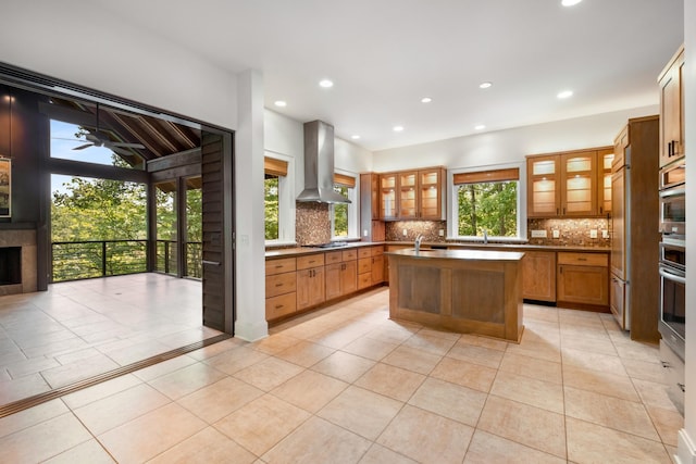 7909 Shoals Branch Rd, Primm Springs, TN 38476 - kitchen featuring island exhaust hood, a kitchen island with sink, tasteful backsplash, light tile patterned flooring, and glass insert cabinets