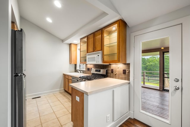 7909 Shoals Branch Rd, Primm Springs, TN 38476 - kitchen with appliances with stainless steel finishes, decorative backsplash, a peninsula, light countertops, and brown cabinetry