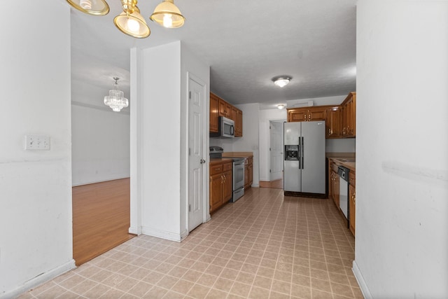 772 Blakemore Rd, Dickson, TN 37055 - kitchen with appliances with stainless steel finishes, light floors, a chandelier, brown cabinets, and light countertops