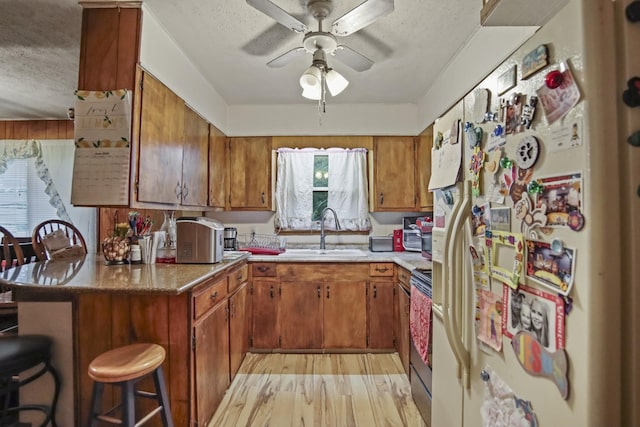 117 Hill Rd, Ardmore, TN 38449 - kitchen with stainless steel appliances, brown cabinets, a textured ceiling, a peninsula, and a ceiling fan