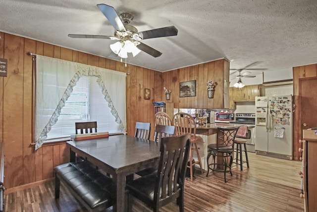 117 Hill Rd, Ardmore, TN 38449 - dining room with ceiling fan, light wood-style flooring, wood walls, and a textured ceiling