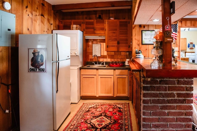 4295 Cairo Bend Rd, Lebanon, TN 37087 - kitchen featuring freestanding refrigerator, wood walls, stacked washing machine and dryer, electric panel, and dark countertops