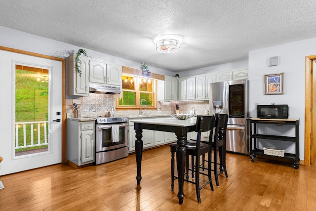 5719 Minor Hill Hwy, Goodspring, TN 38460 - kitchen with stainless steel appliances, under cabinet range hood, decorative backsplash, light countertops, and light wood-type flooring