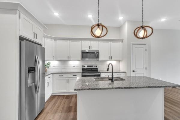 187 Charleston Ave, Pleasant View, TN 37146 - kitchen with appliances with stainless steel finishes, wood finished floors, dark stone counters, white cabinets, and tasteful backsplash