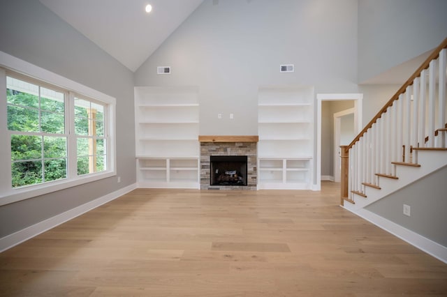 11497 Karo Rd, Bell Buckle, TN 37020 - unfurnished living room featuring high vaulted ceiling, built in features, light wood-style flooring, stairs, and a stone fireplace