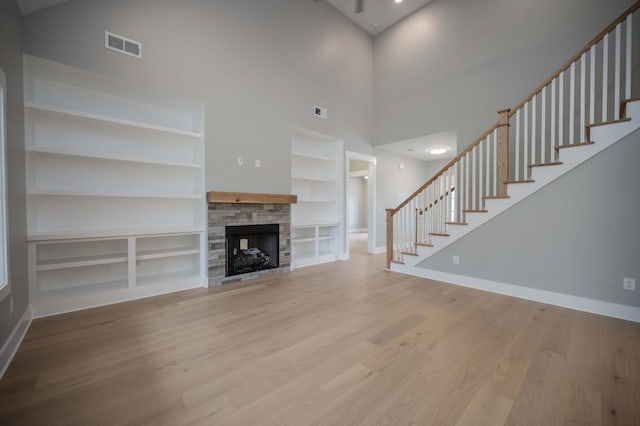 11497 Karo Rd, Bell Buckle, TN 37020 - unfurnished living room with stairs, built in features, wood finished floors, a high ceiling, and a fireplace