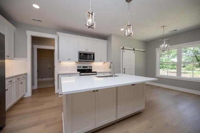 11497 Karo Rd, Bell Buckle, TN 37020 - kitchen featuring appliances with stainless steel finishes, a barn door, decorative backsplash, light wood-style flooring, and recessed lighting