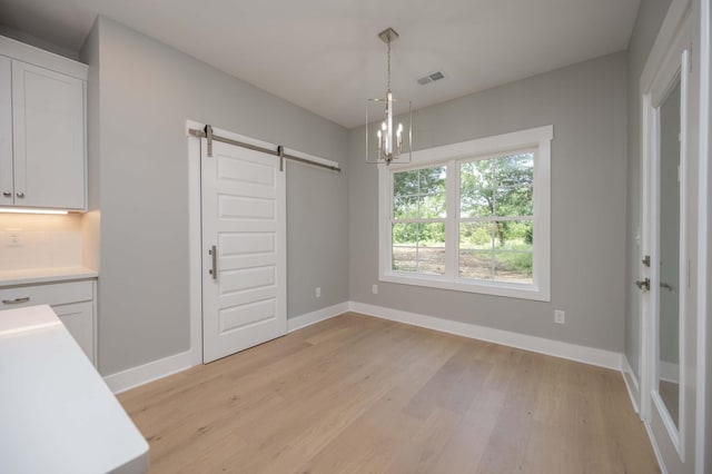 11497 Karo Rd, Bell Buckle, TN 37020 - unfurnished dining area with a barn door, light wood-type flooring, and a chandelier