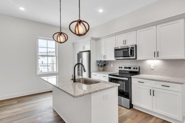191 Charleston Ave, Pleasant View, TN 37146 - kitchen featuring appliances with stainless steel finishes, white cabinetry, light wood-style floors, a center island with sink, and backsplash