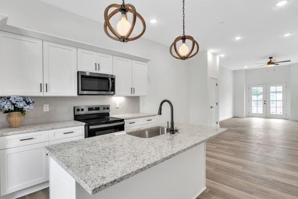 191 Charleston Ave, Pleasant View, TN 37146 - kitchen with appliances with stainless steel finishes, white cabinets, a center island with sink, light wood finished floors, and decorative light fixtures