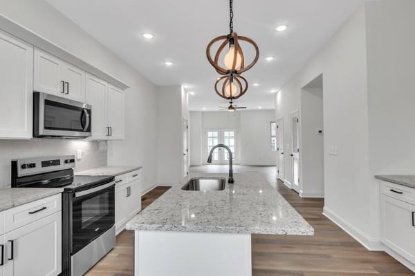 191 Charleston Ave, Pleasant View, TN 37146 - kitchen featuring appliances with stainless steel finishes, an island with sink, white cabinets, light wood finished floors, and pendant lighting