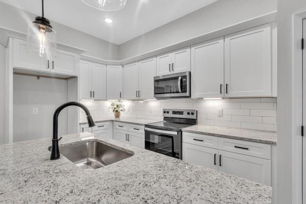 195 Charleston Ave, Pleasant View, TN 37146 - kitchen featuring appliances with stainless steel finishes, white cabinets, backsplash, decorative light fixtures, and light stone countertops