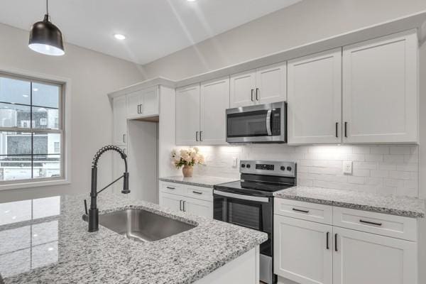 203 Charleston Ave, Pleasant View, TN 37146 - kitchen featuring appliances with stainless steel finishes, white cabinetry, tasteful backsplash, decorative light fixtures, and light stone countertops