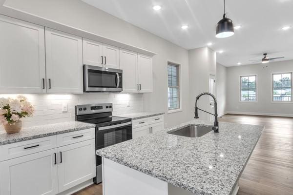 203 Charleston Ave, Pleasant View, TN 37146 - kitchen featuring appliances with stainless steel finishes, ceiling fan, a center island with sink, white cabinets, and backsplash