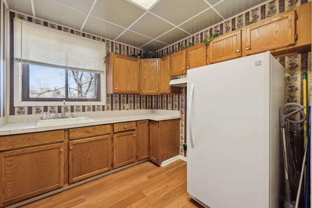 305 Myers Ter, Carthage, TN 37030 - kitchen featuring freestanding refrigerator, wallpapered walls, light wood-type flooring, brown cabinetry, and under cabinet range hood