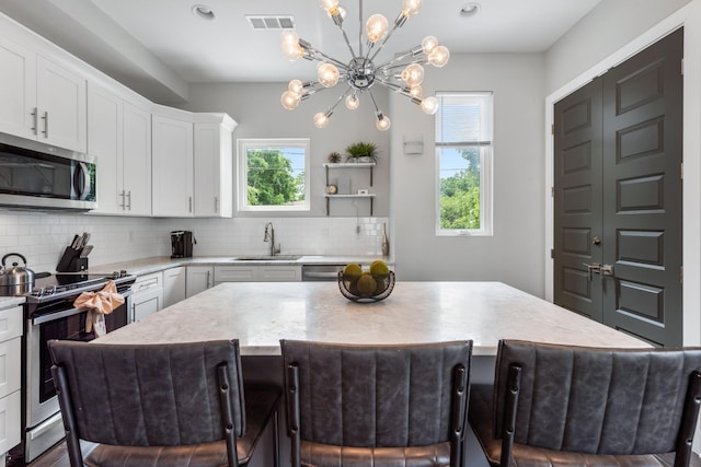 2410 Meharry Blvd Unit 3, Nashville, TN 37208 - kitchen featuring stainless steel appliances, tasteful backsplash, a center island, white cabinetry, and a chandelier