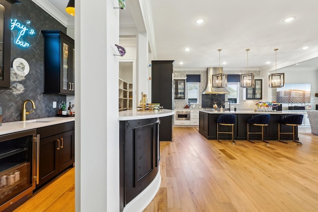 6004 Lookaway Cir, Franklin, TN 37067 - kitchen with beverage cooler, wall chimney range hood, ornamental molding, a kitchen bar, and light countertops