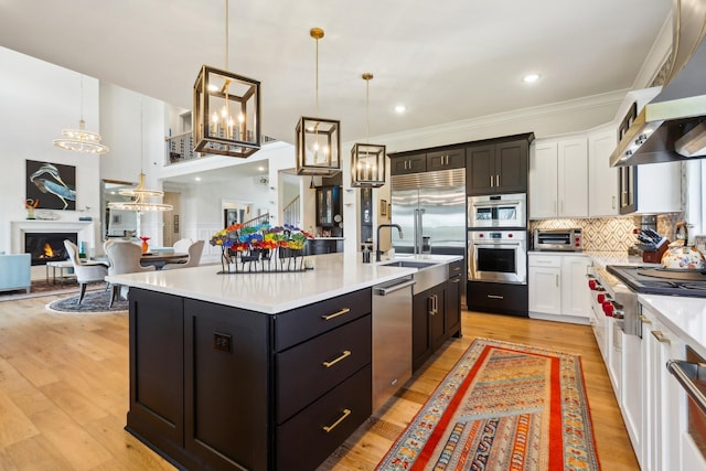 6004 Lookaway Cir, Franklin, TN 37067 - kitchen with stainless steel appliances, wall chimney range hood, white cabinets, open floor plan, and ornamental molding