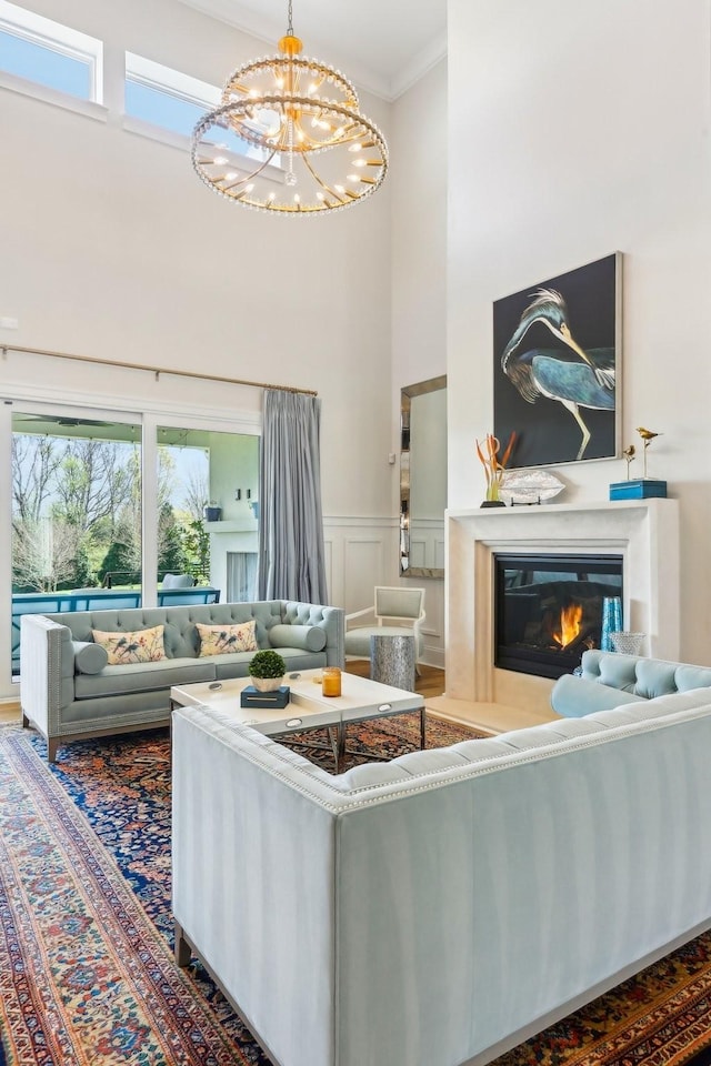 6004 Lookaway Cir, Franklin, TN 37067 - living area featuring ornamental molding, a towering ceiling, a chandelier, a glass covered fireplace, and a wainscoted wall