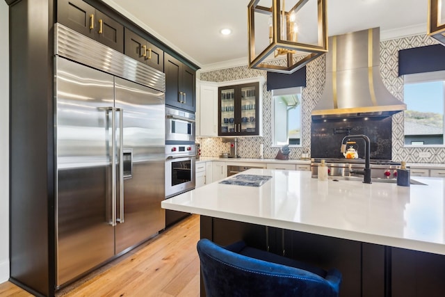 6004 Lookaway Cir, Franklin, TN 37067 - kitchen with built in refrigerator, wall chimney range hood, light wood finished floors, light countertops, and plenty of natural light