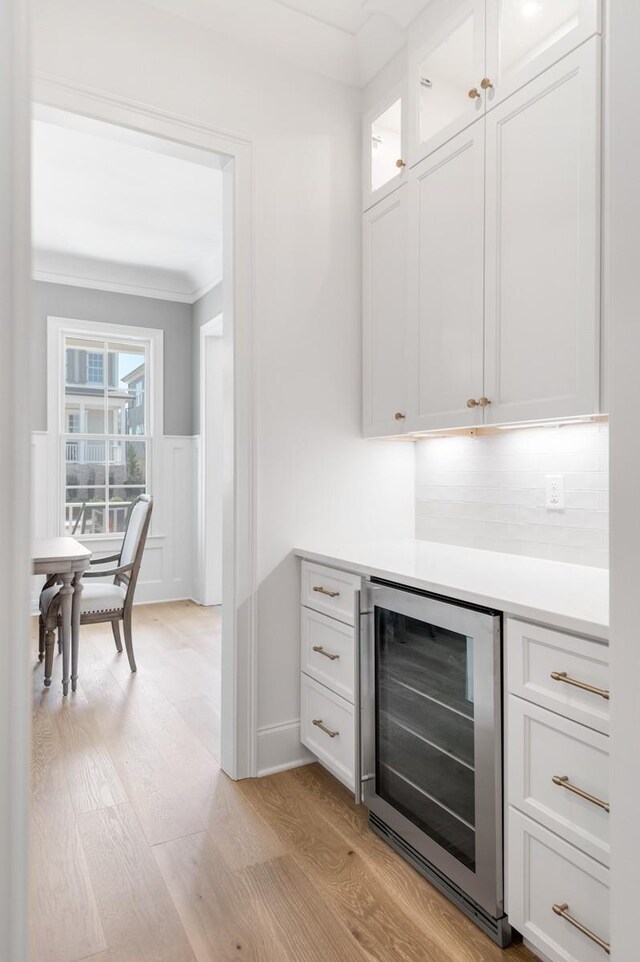 7018 Southvale Blvd, Franklin, TN 37064 - indoor dry bar with wine cooler, ornamental molding, light wood finished floors, tasteful backsplash, and wainscoting