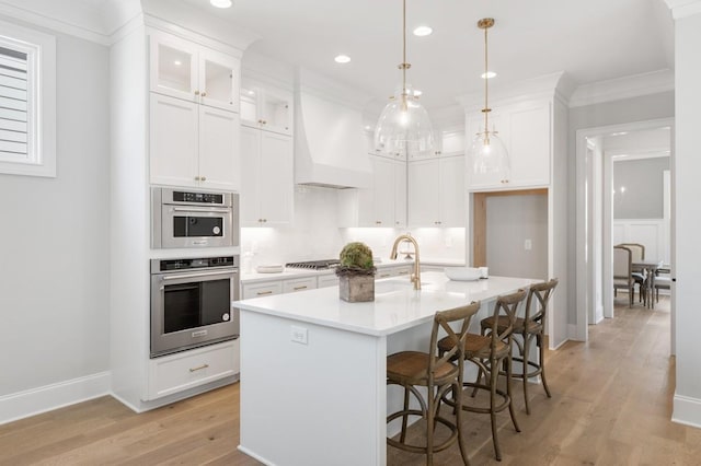 7018 Southvale Blvd, Franklin, TN 37064 - kitchen featuring premium range hood, light wood finished floors, white cabinetry, light countertops, and ornamental molding