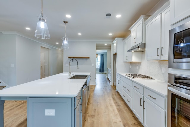 2110 Lequire Ln, Spring Hill, TN 37174 - kitchen featuring appliances with stainless steel finishes, light countertops, ornamental molding, white cabinetry, and under cabinet range hood