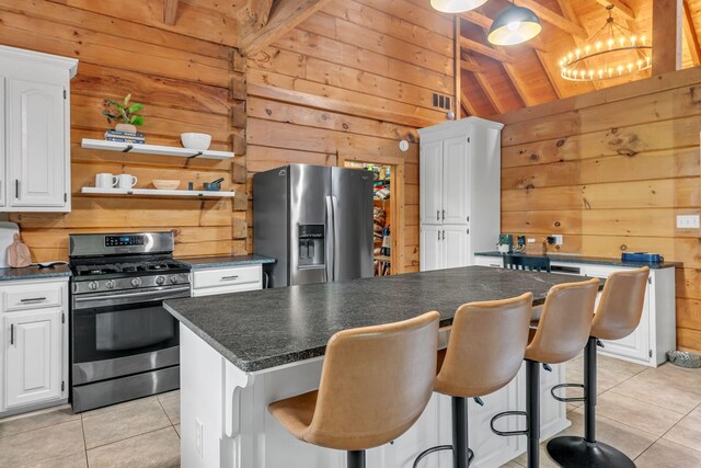 3316 Burr Rd, Springfield, TN 37172 - kitchen featuring appliances with stainless steel finishes, wood walls, light tile patterned floors, dark countertops, and a kitchen island