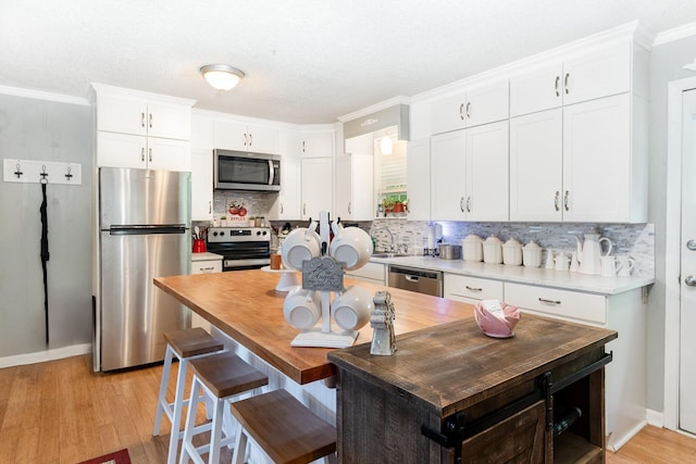 106 Hogin Rd, Dickson, TN 37055 - kitchen featuring stainless steel appliances, decorative backsplash, white cabinetry, and crown molding