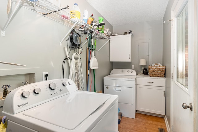 106 Hogin Rd, Dickson, TN 37055 - laundry area featuring washing machine and clothes dryer, light wood finished floors, cabinet space, and a textured ceiling