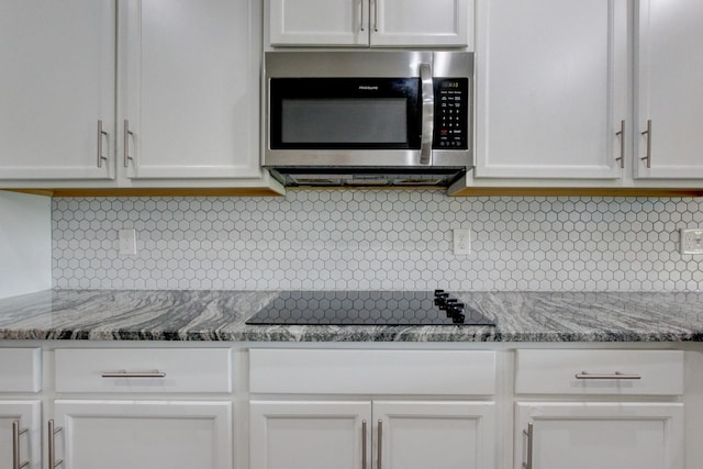 1331 Juniper Pass, Clarksville, TN 37043 - kitchen with stainless steel microwave, black electric stovetop, white cabinetry, and backsplash