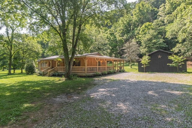 5191 Still House Hollow Rd, Franklin, TN 37064 - view of green lawn featuring covered porch, driveway, a forest view, and an outdoor structure