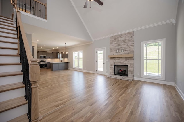 135 Bruce Meadows Dr, Beechgrove, TN 37018 - unfurnished living room with crown molding, a ceiling fan, a stone fireplace, stairs, and light wood-style flooring