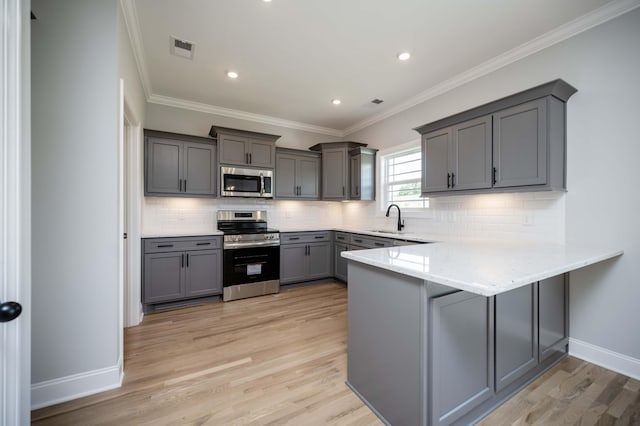 135 Bruce Meadows Dr, Beechgrove, TN 37018 - kitchen featuring appliances with stainless steel finishes, gray cabinetry, a peninsula, light wood-style floors, and tasteful backsplash