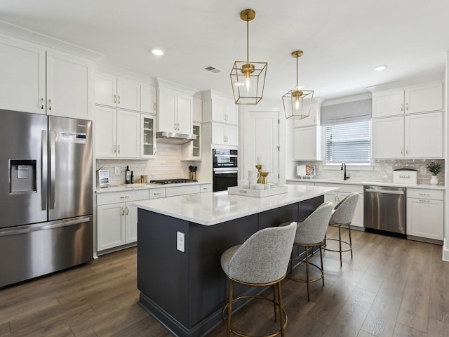 7019 Chardon St, Franklin, TN 37067 - kitchen with stainless steel appliances, a breakfast bar area, white cabinets, a kitchen island, and recessed lighting