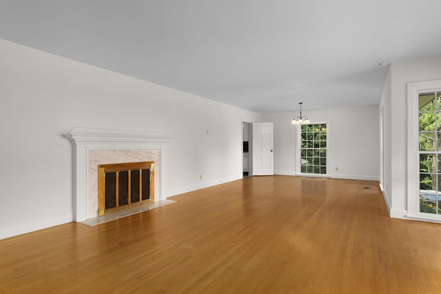 2411 Woolson Rd, Chattanooga, TN 37406 - unfurnished living room featuring light wood-style flooring, a chandelier, plenty of natural light, and a high end fireplace