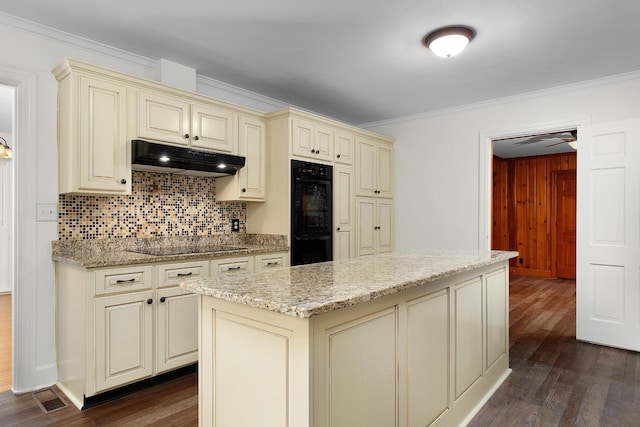 2411 Woolson Rd, Chattanooga, TN 37406 - kitchen featuring cream cabinetry, under cabinet range hood, crown molding, black appliances, and dark wood-type flooring