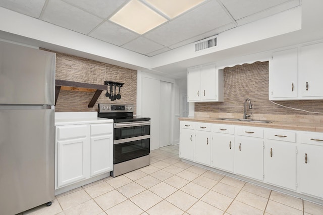 2411 Woolson Rd, Chattanooga, TN 37406 - kitchen with stainless steel appliances, tasteful backsplash, white cabinets, light tile patterned flooring, and a drop ceiling