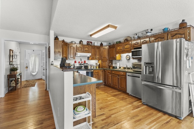 3330 Booker Farm Rd, Mount Pleasant, TN 38474 - kitchen with stainless steel appliances, dark countertops, light wood-style flooring, brown cabinets, and a textured ceiling
