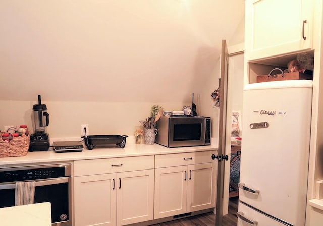450 Lowe Branch Rd, Centerville, TN 37033 - kitchen with stainless steel appliances, light countertops, vaulted ceiling, dark wood finished floors, and white cabinetry