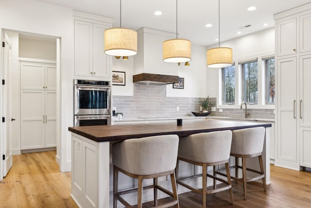 1249 Wilson School Rd, Chapel Hill, TN 37034 - kitchen featuring double oven, a kitchen island, wood counters, decorative backsplash, and light wood-style flooring
