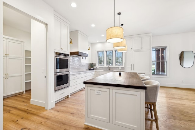 1249 Wilson School Rd, Chapel Hill, TN 37034 - kitchen featuring double oven, a breakfast bar, light wood-style floors, white cabinetry, and tasteful backsplash