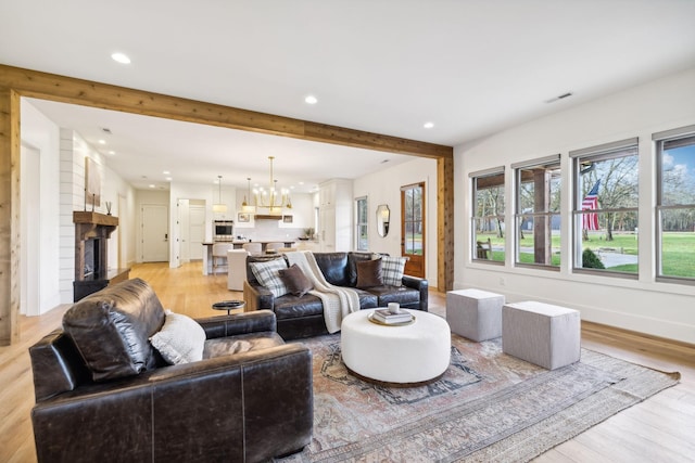 1249 Wilson School Rd, Chapel Hill, TN 37034 - living room with a chandelier, recessed lighting, beam ceiling, a fireplace with raised hearth, and light wood-style floors