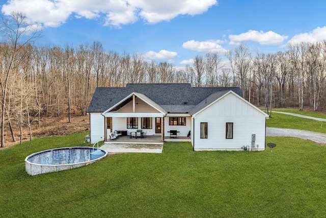 673 Billy Wynn Rd, Dickson, TN 37055 - back of property featuring board and batten siding, a lawn, an outdoor pool, a patio area, and a shingled roof